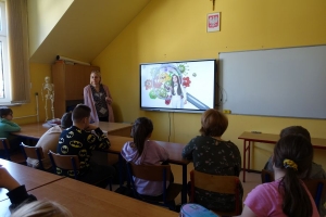 Uczniowie przy stolikach rysują, ogladają film.