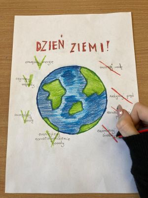 zdjęcie przedstawiające narysowaną na kartce planetę oraz dłoń z długopisem